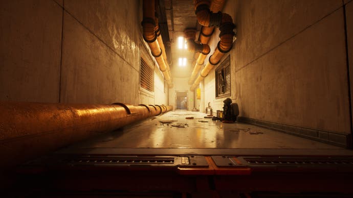 A yellow-glowing and fairly shiny-surfaced corridor on a ruined facility at sea. Thick pipes stretch down it and a humanoid robot is slumped on the floor.