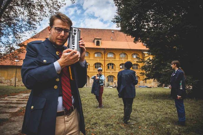 A man holds an electronic device to their ear during a Disco Elysium LARP.