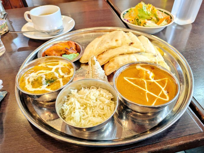 Photo of a curry meal with cheese naan to the side