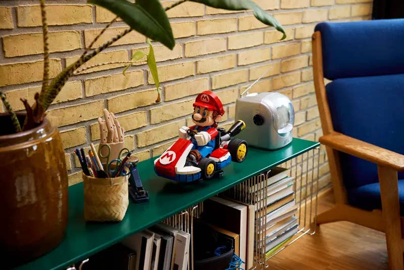 A sizeable Mario Kart Lego build on a shelf, next to some pens and a pencil sharpener. It's as if Mario is trying to escape being sharpened to a point himself.